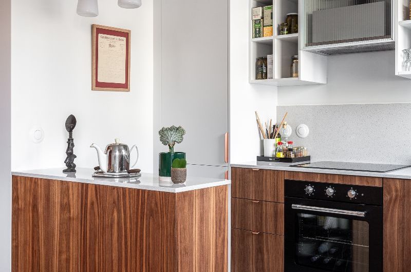 A small kitchen design with wood units, a matching peninsula, open shelving and large-format terrazzo floor tiles.
