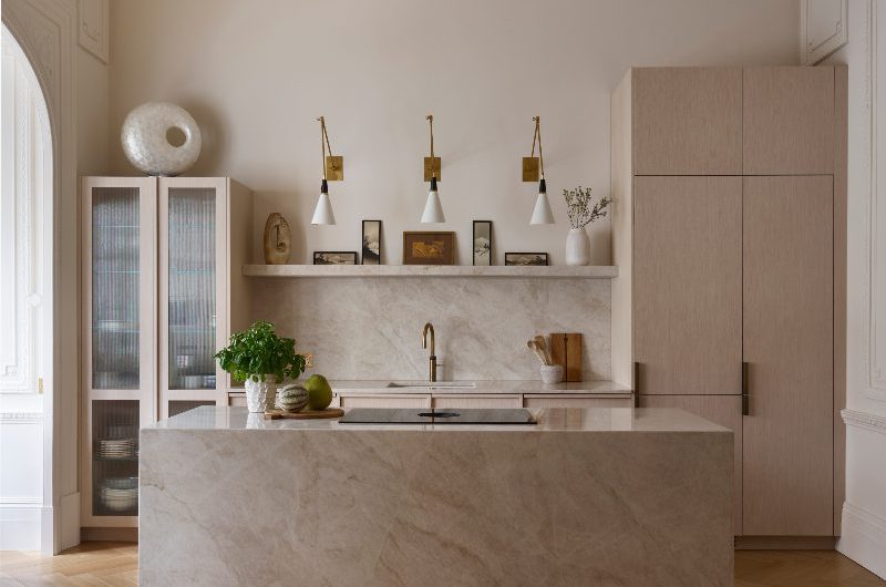 A modern neutral kitchen with timeless cabinetry, herringbone flooring, and a palette of dusky pinks, chalky whites, and pale sage greens.