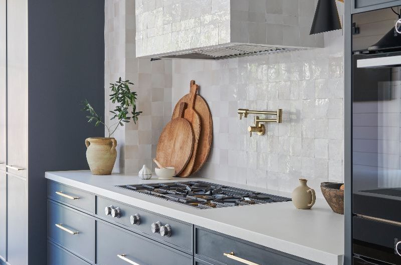A kitchen with a coastal feel, contemporary details, tactile tiles, and dark blue cabinets.