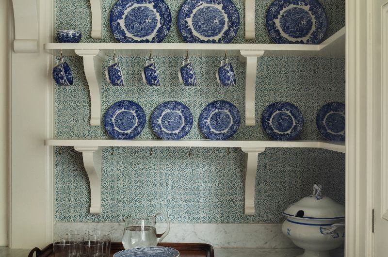 A classic scheme with blue and white ceramics on open shelves, cream Shaker cabinets, and marble worktops.