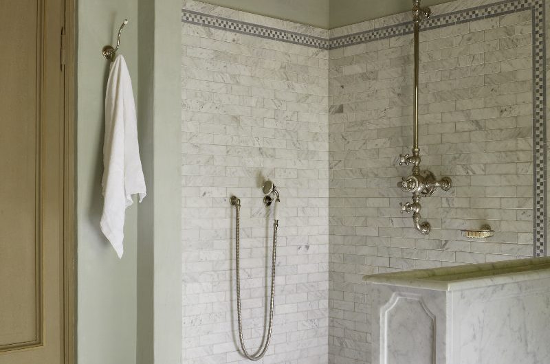 A classic bathroom with small marble metro tiles, classic brassware, and checkerboard flooring.