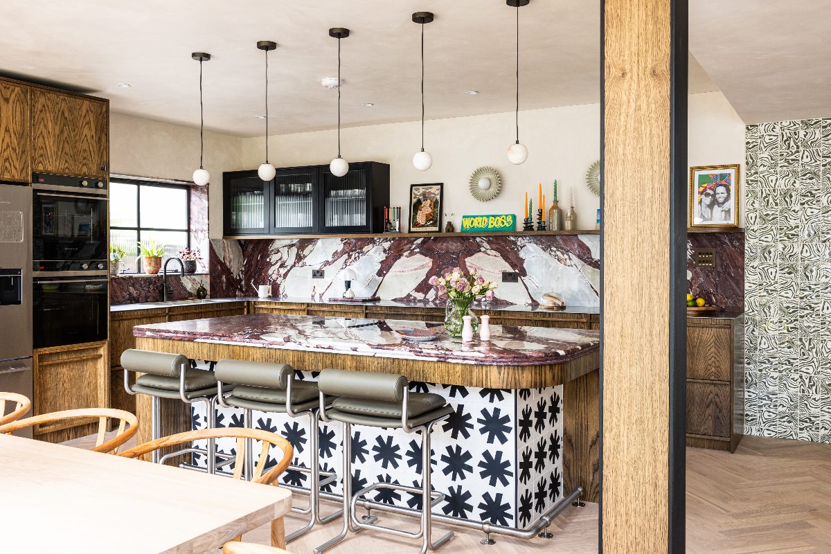 A mid-century scheme with calacatta viola marble, wood cabinetry, industrial-style lighting, and patterned tiles adorning a central island.