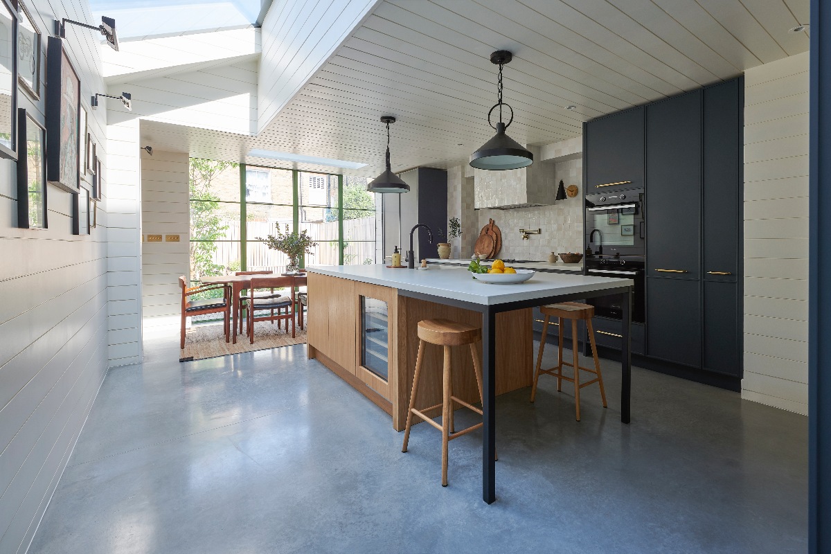 A spacious and airy kitchen design with dark blue cabinets, a wood island, and painted boards on the wall and ceiling.