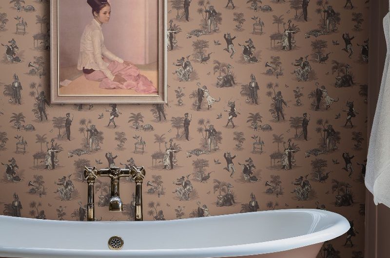 A colourful bathroom with patterned wallpaper, a painted freestanding tub with brass feet, and a chunky bath filler.