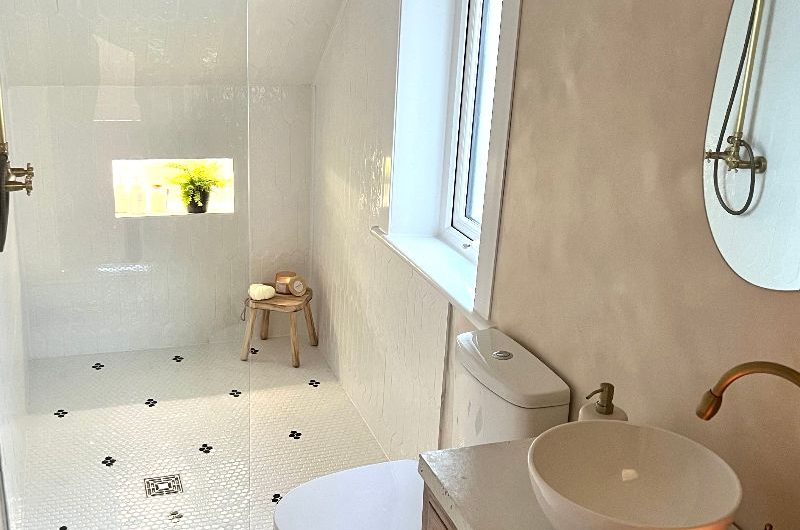 A spa like bathroom renovation with mosaic floor tiles, limewash paint, a wood vanity and a shower zone.