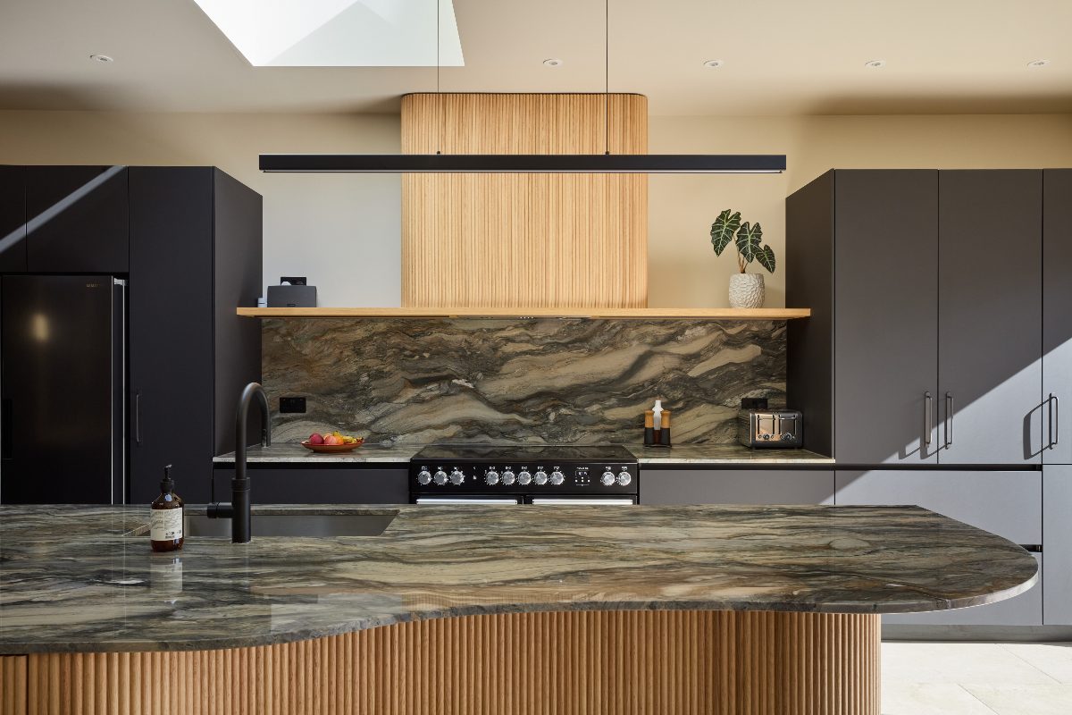 A modern kitchen design with sleek matt black cabinetry contrasted with warm natural wood accents and statement stone.