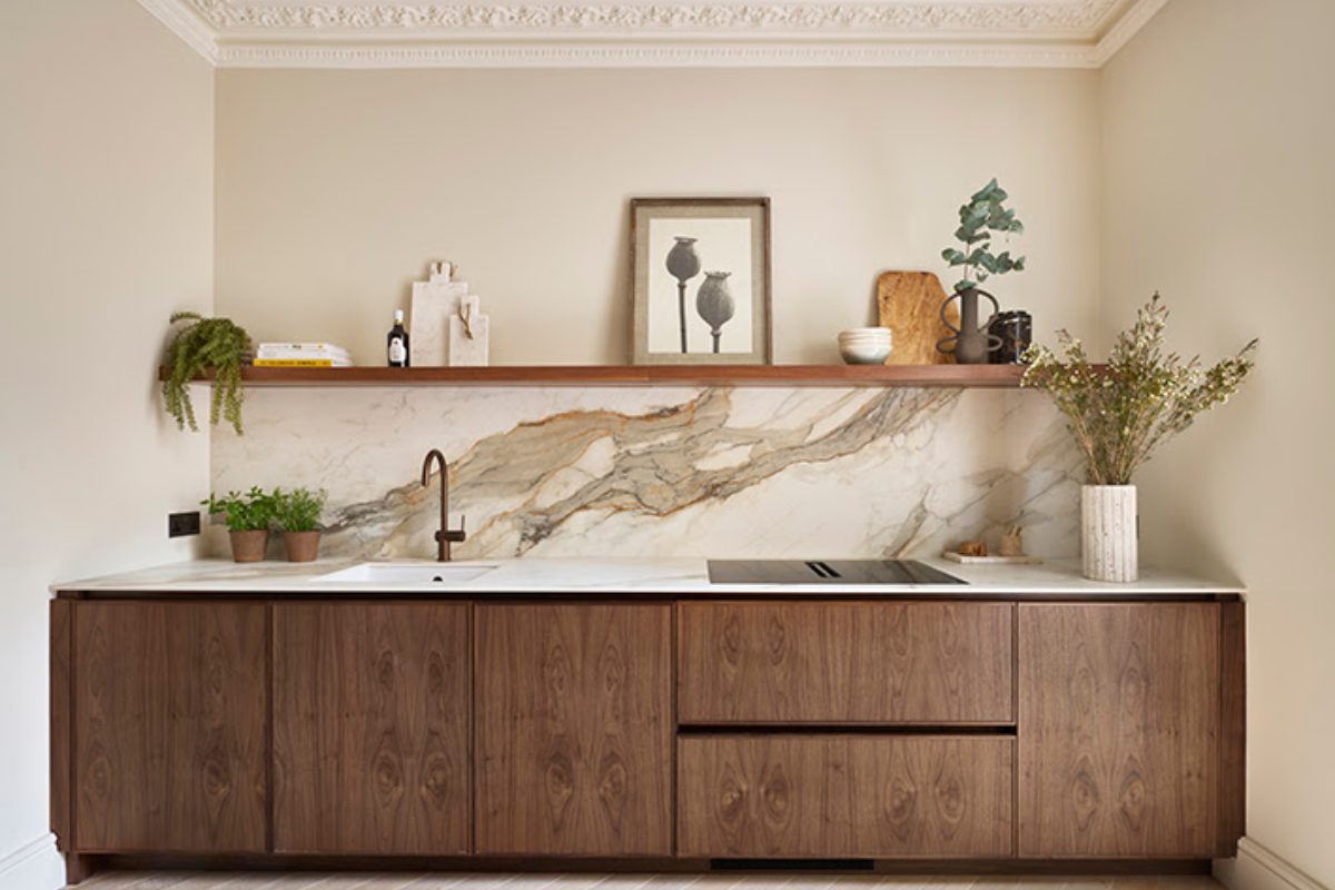 Closeup at a single galley layout with slim Shaker wood units, single slab splashback and wood open shelving.