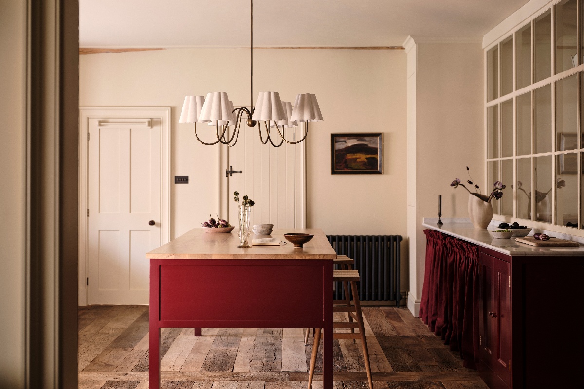 A country chic kitchen with a freestanding island, wood flooring, and statement pendant light.