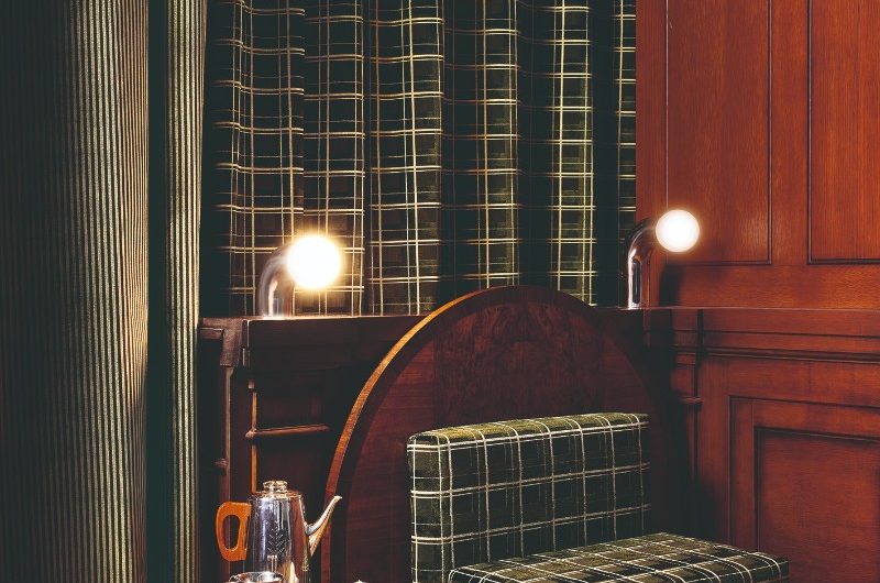 A statement seating area with an upholstered seat, wood furniture, and chunky, patterned curtains.