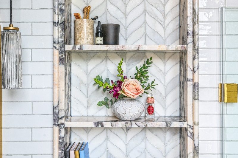 Closeup at a storage alcove with marble materials above the toilet.