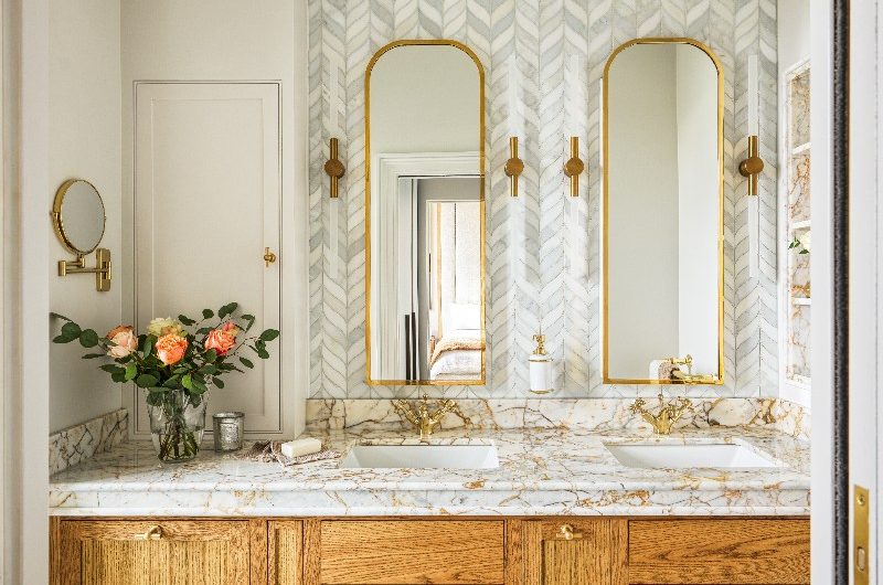 A luxury ensuite with a double oak vanity, veined marble, and polished gold brassware.