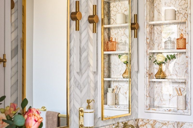 Closeup at the double oak vanity with warm veined marble and polished gold fittings and fixtures.