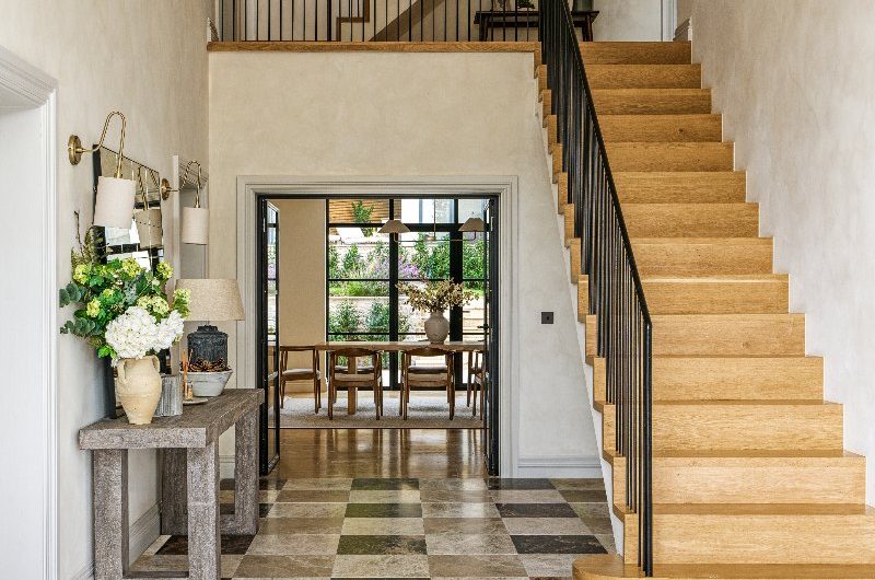 A luxurious entryway design with wood stairs and marble flooring.