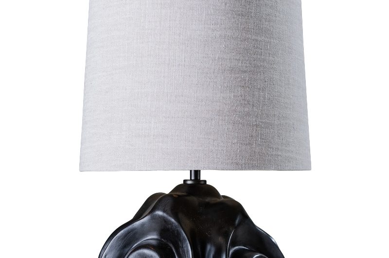 A statement lamp with a black, textured base and linen shade.