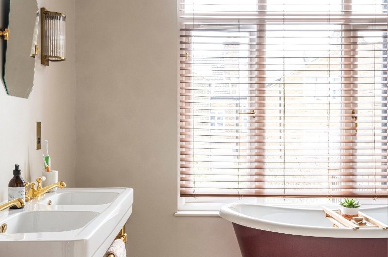 A bathroom design with a double sink, green patterned tiles, and roll top bath.