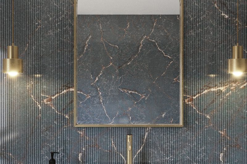 A bathroom design with fluted wall surfaces, a white basin, gold tap, mirror and lighting.