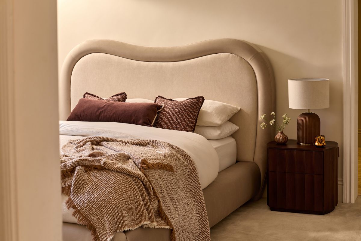 A boutique hotel bedroom with a grand bed and fluted bedside table.