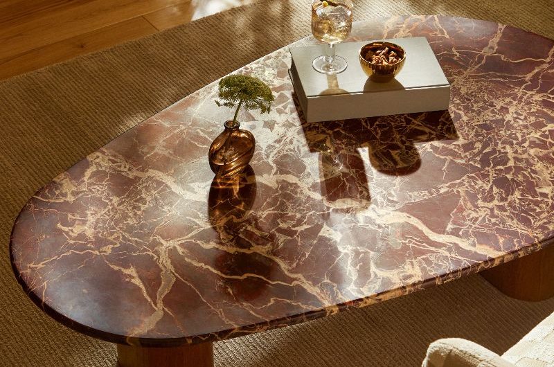 Closeup at a red marble coffee table with a textured rug underneath.