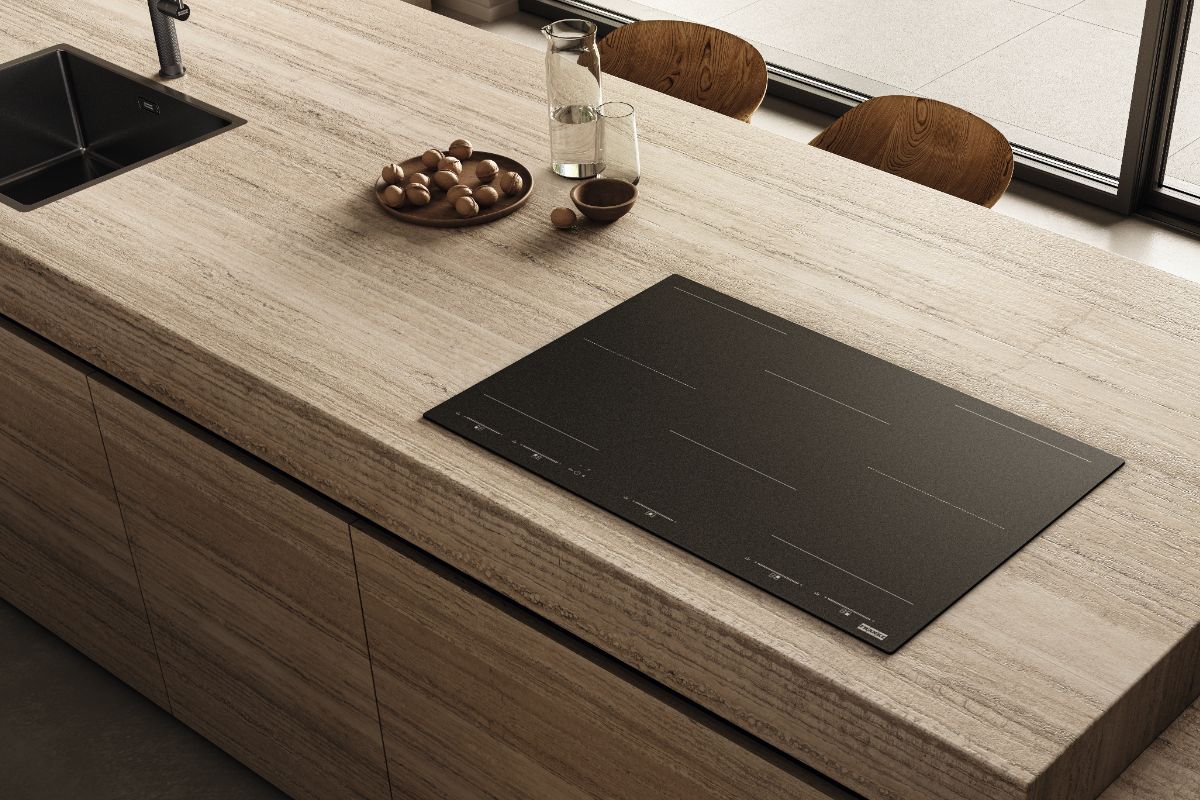 A modern kitchen island with stone surfaces and a matt induction hob.
