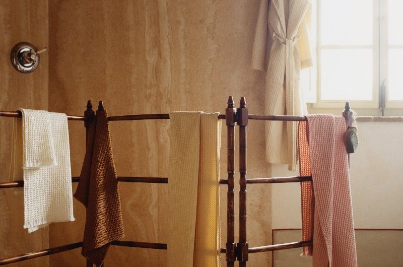 A Mediterranean-style bathroom with chrome brassware, textured wall and floor tiles, and waffle towels.