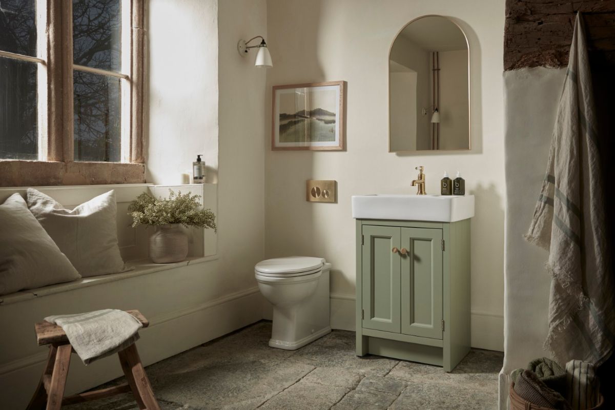 A rustic bathroom design with stone flooring, a green vanity, and a window seat.