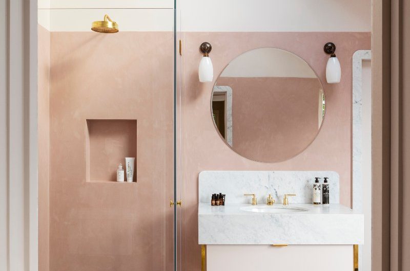 A pink bathroom design with marble flooring and matching shower tray, a storage niches, a modern vanity, and pink microcement on the walls.