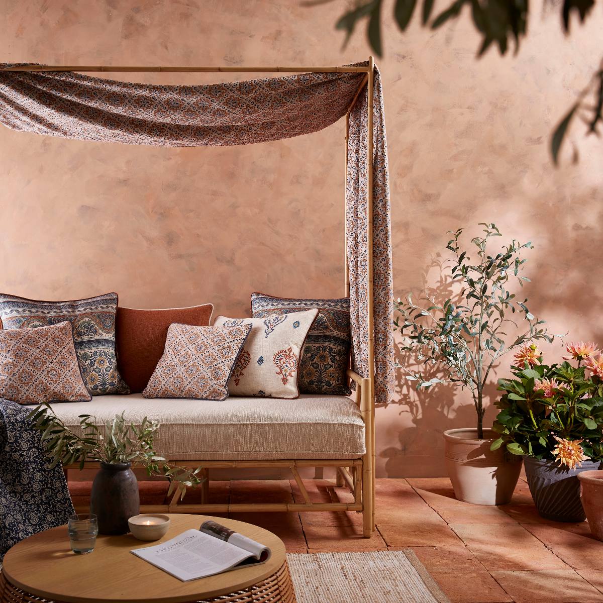 A garden zone with plaster and terracotta flooring, and a mix of global-inspired patterned curtains and cushions.