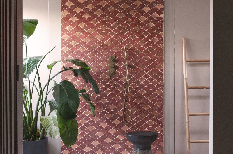 An exotic bathroom with scalloped tiles in the shower and patterned flooring.