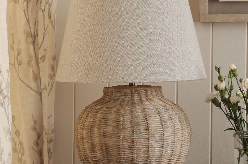 Closeup at a rattan table lamp with a cream shade.