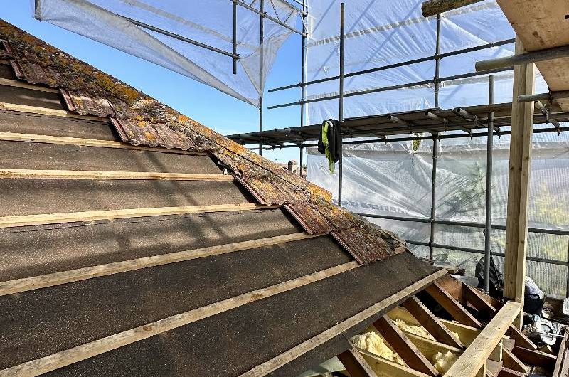 Scaffolding towering over the original roof of the house.