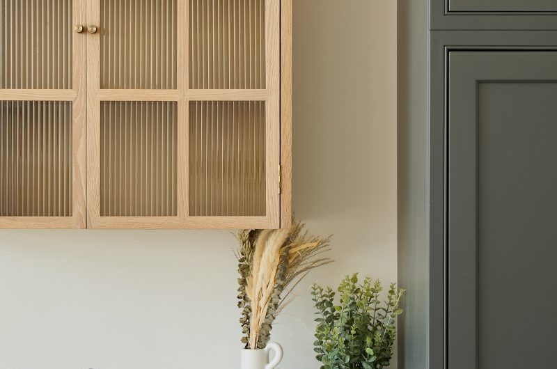 Closeup at a kitchen design with a wall-mounted unit with fluted glass fronts.