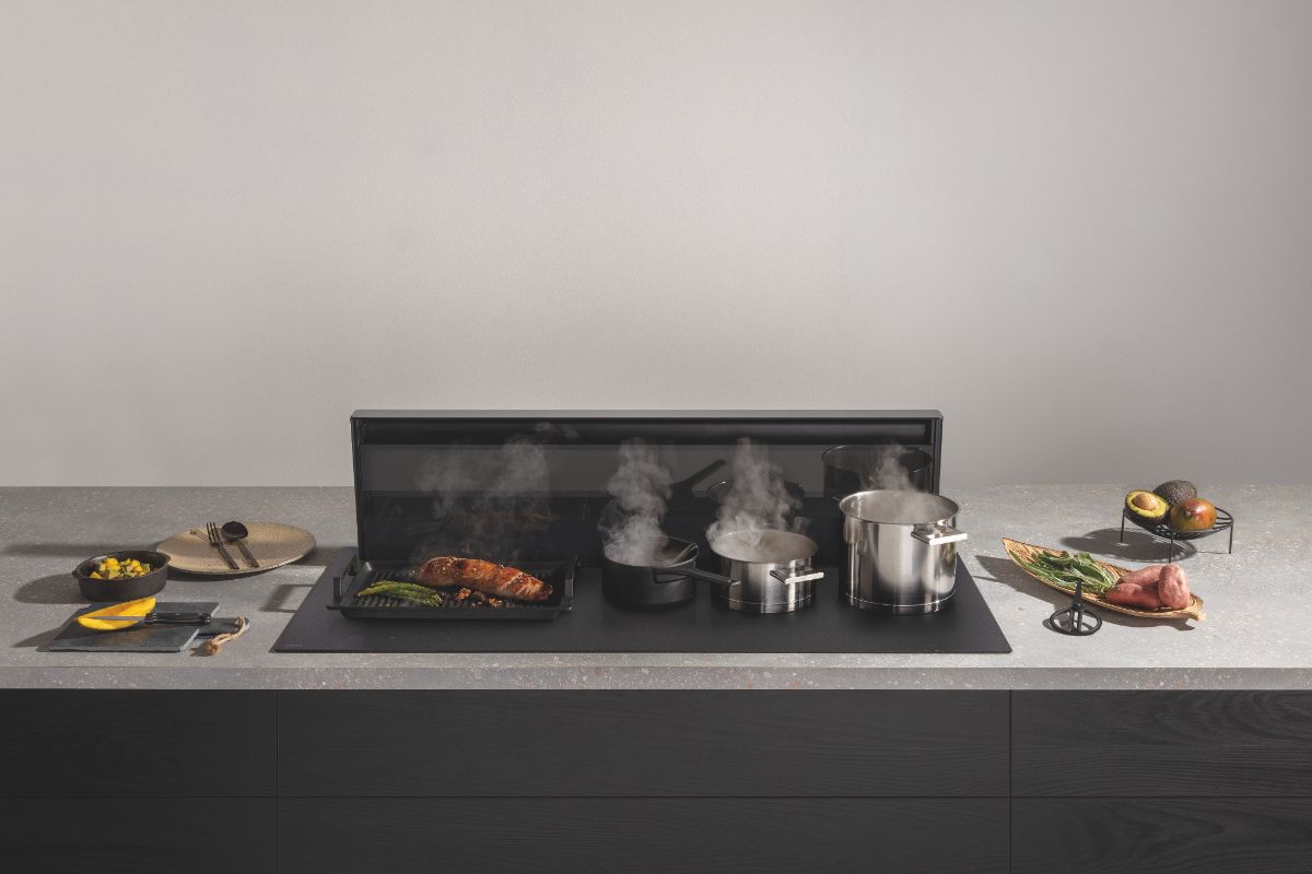 A dark wood kitchen design with a grey speckled work surface, a downdraft extractor and sleek cooking appliance.