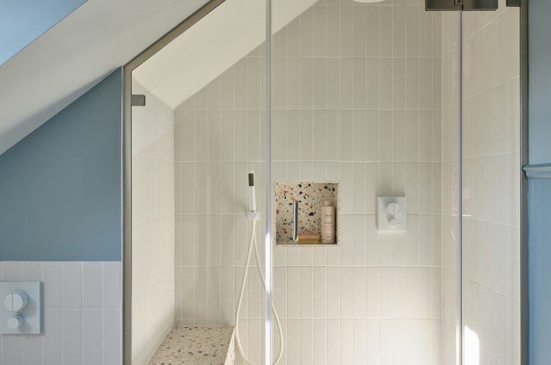 A shower zone with a terrazzo seat and matching niche, and white wall tiles, brassware, and shower tray.