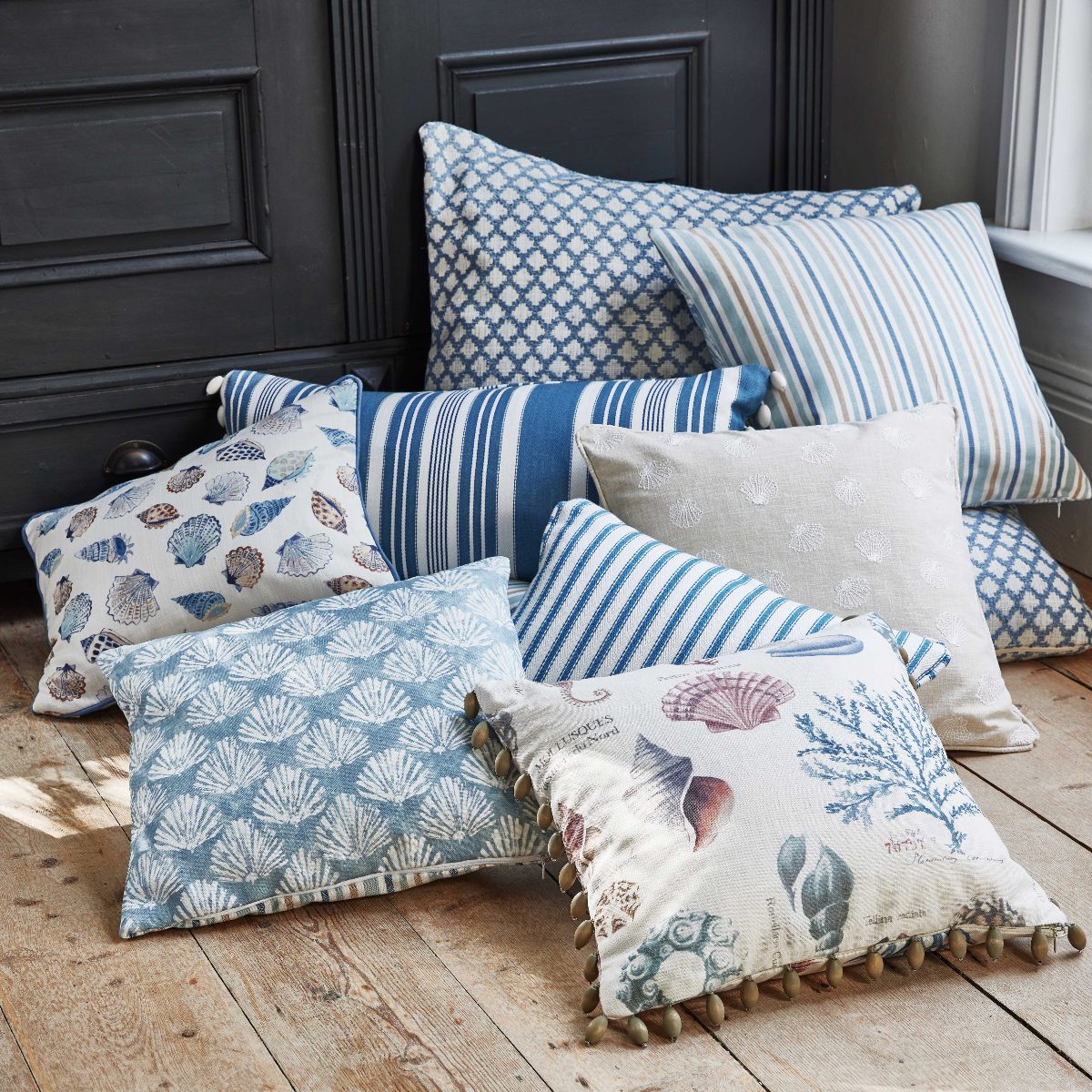 A collection of coastal patterned cushions on a wooden floor.