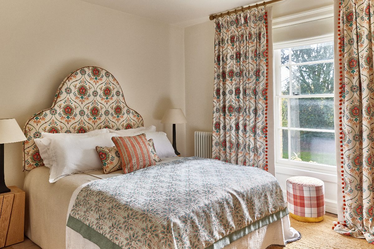 A classic bedroom design with neutral wall paint, jute rug, and global-inspired patterned fabrics.