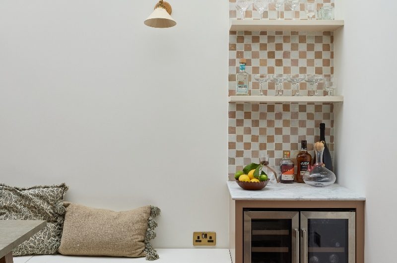A bar area with a double wine fridge and checkerboard wall tiles.