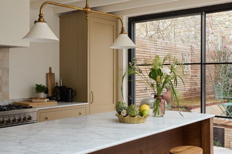 Closeup at a freestanding wood island with marble worktop and three bar stools.
