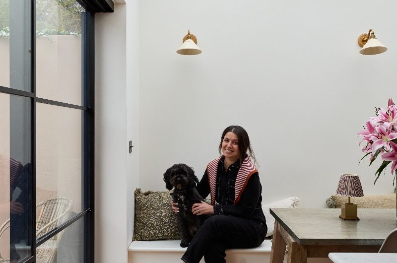 Homeowner sitting on the dining area bench next to glazing with her dog.