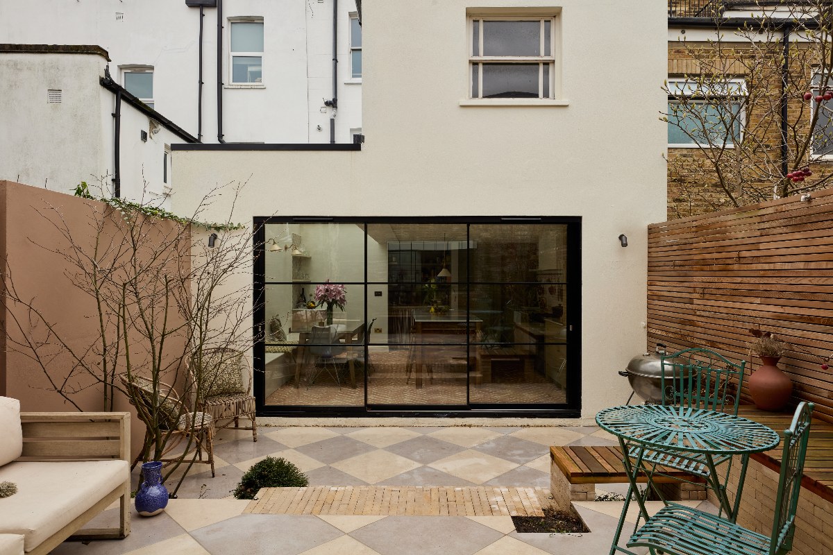 View of the outside of the extension with steel glazing and a glass roof, and a garden with a Mediterranean feel.
