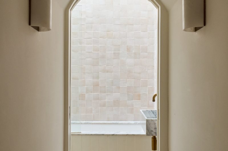 An arched doorway leads into the serene bathroom.