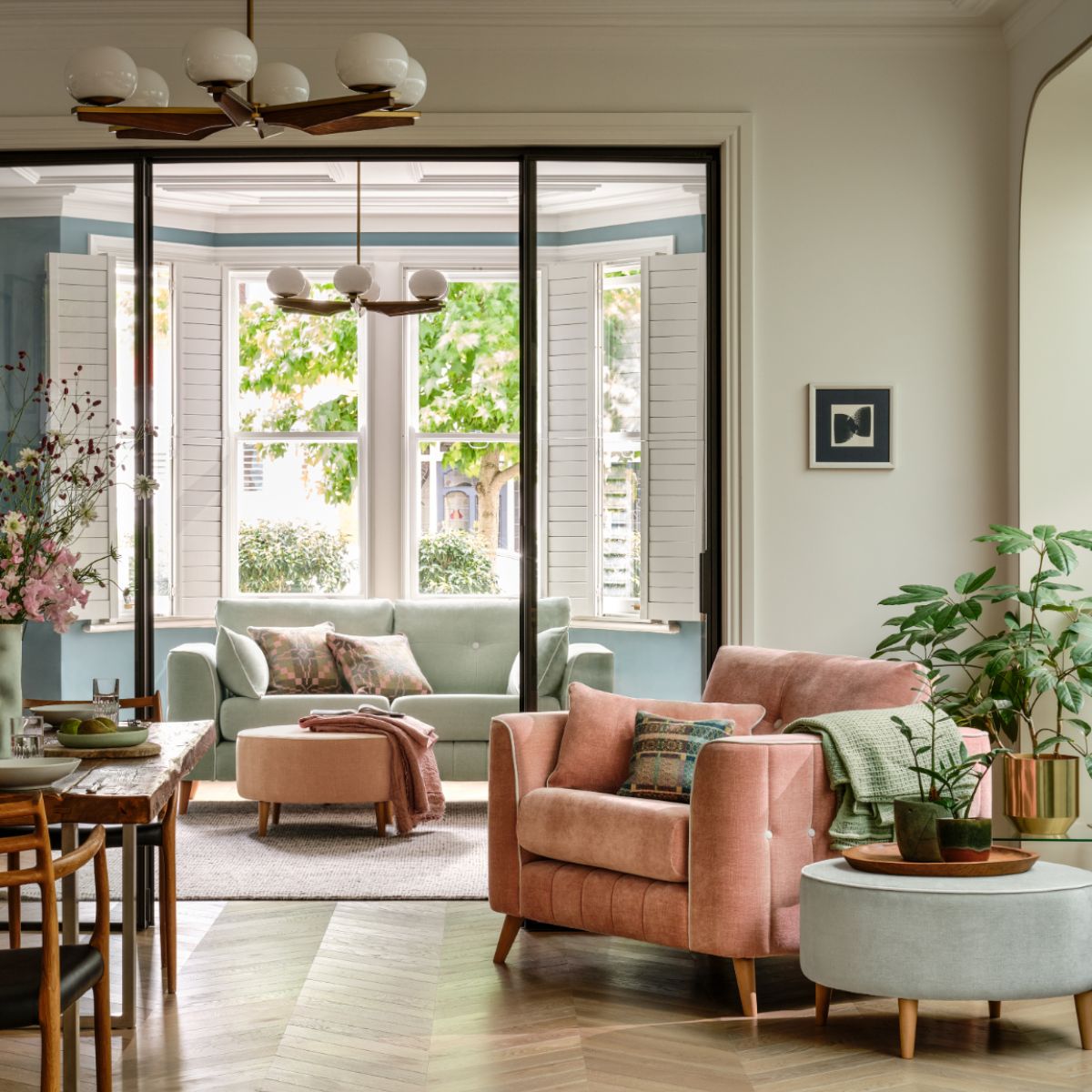 A spring living and dining room with pastel furniture, herringbone flooring, internal glazing, and wide windows.