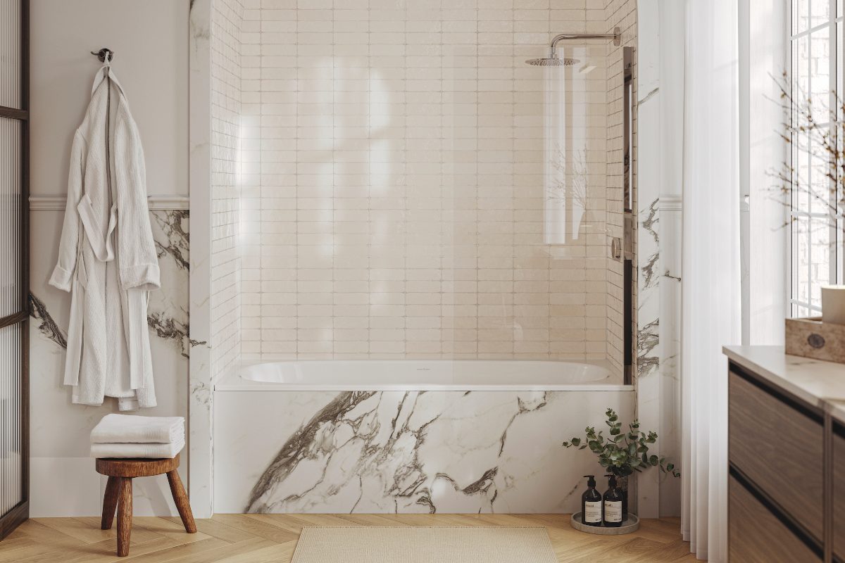 A boutique hotel bathroom with a fitted bath clad in marble-effect surface, wood vanity, chrome brassware, and spa decor.