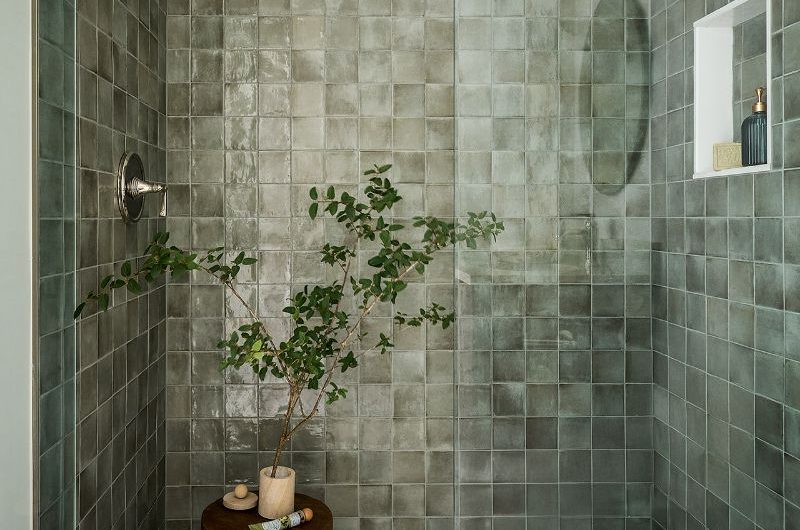 A spa-like bathroom with green zellige tiles and rustic decor.
