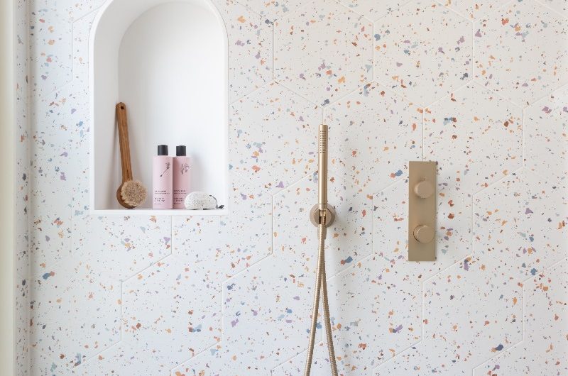 A bathroom with terrazzo wall tiles and a storage niche in the shower.