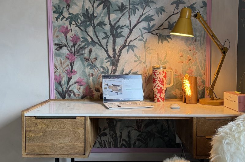 A home office renovation with a wooden desk with a glossy countertop with a floral print in the background.