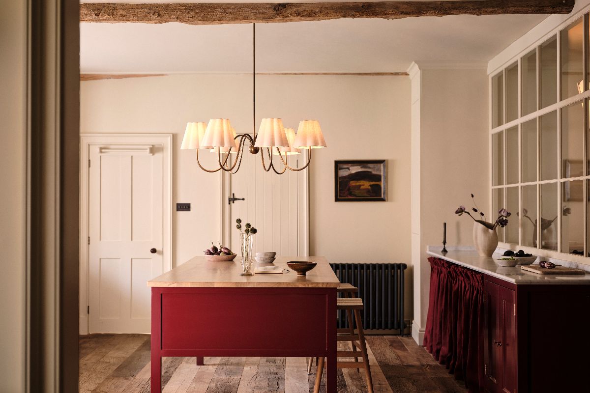 A kitchen design with a red freestanding island, statement lighting, and an adjacent pantry.