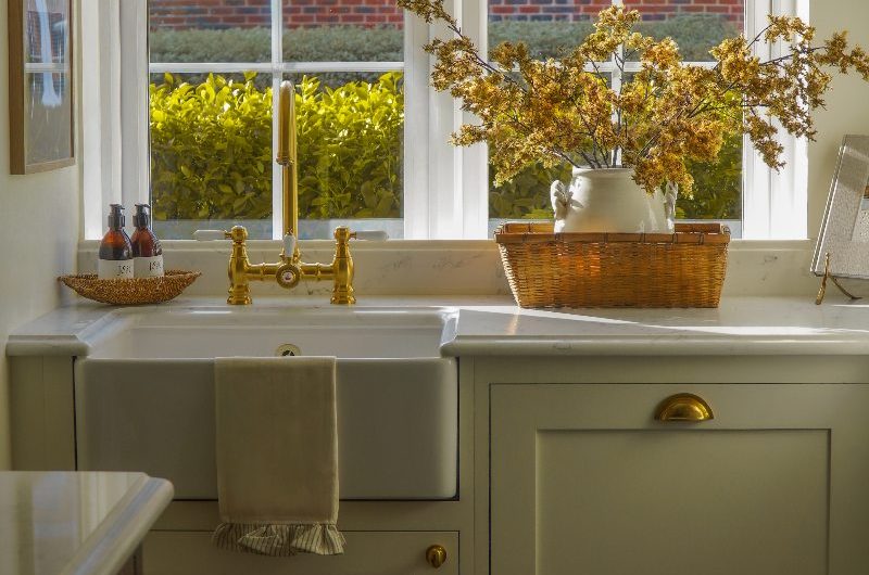 A timeless kitchen design with classic cabinetry, a butler sink, gold tap, and a wood island.