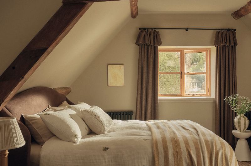 A rustic bedroom design with exposed wooden beams, tactile bed linen and chunky throws and curtains.