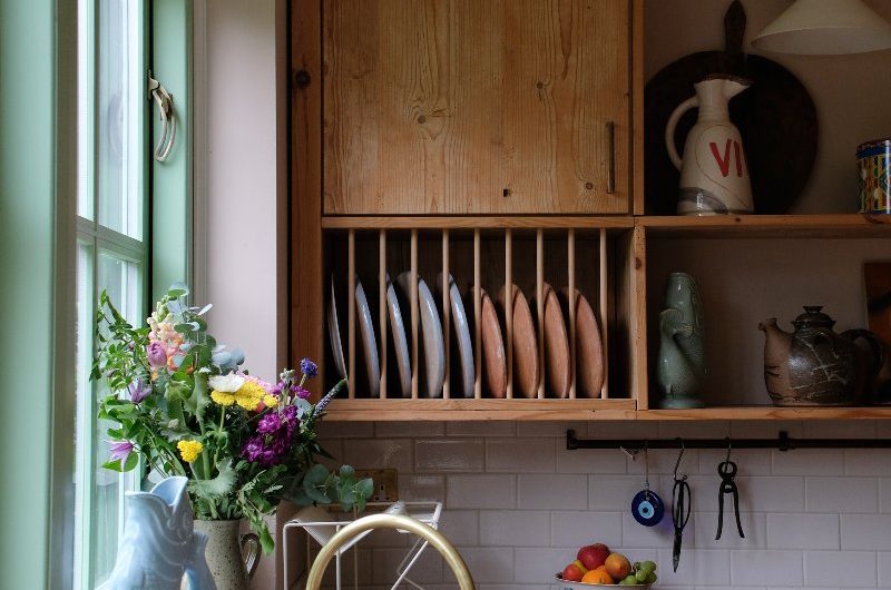 A rustic kitchen with wooden units and worktops, metro tiles, and a built-in plate rack near the sink zone.