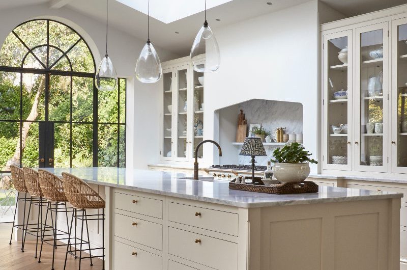 A timeless kitchen renovation with neutral cabinetry, glazed cupboards, wood flooring, skylights, and a central multi-functional island.